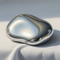 A smooth bean shaped metallic object rests on a white textured fabric Royalty Free Stock Photo