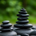 Smooth black pebbles are stacked in two piles against a blurred green background. Royalty Free Stock Photo