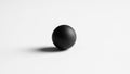 Black sphere sits on a plain white surface casting a soft shadow Royalty Free Stock Photo