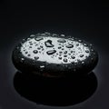 Smooth, black stone with glossy surface covered in water droplets, creating a Royalty Free Stock Photo