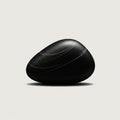 Smooth black stone with a matte finish sits against a plain, light backdrop. The stone Royalty Free Stock Photo