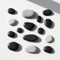 Smooth black and white stones are arranged on a flat, white surface. The stones vary in Royalty Free Stock Photo