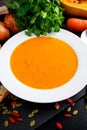 Smooth butternut squash and carrot soup with cream, pumpkin seeds goji berries