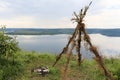 A smooth calm water view. A tent made of twigs on the river banks.