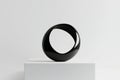 smooth circular form in black, with subtle light reflections that enhance its curves, placed on a