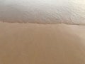 Smooth and clear brown sand beach with white sea waves