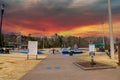 A smooth concrete skatepark surrounded by yellow winter grass, green umbrellas over benches, bare winter trees