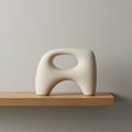 Smooth, cream-colored sculpture with an abstract, amoeba-like shape sits on a light