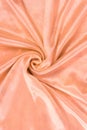 Luxury coral pink or gold rose silk background. Rippled silk fabric, drapery cloth, or satin texture Royalty Free Stock Photo