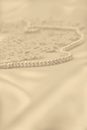 Smooth elegant golden silk or satin with pearls and lace as wedding background. In Sepia toned. Retro style Royalty Free Stock Photo