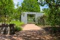 A smooth footpath in the garden with a stone entry way surrounded by lush green trees, grass and plants with gorgeous blue sky Royalty Free Stock Photo