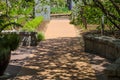 A smooth footpath in the garden with a stone entry way surrounded by lush green trees, grass and plants with gorgeous blue sky Royalty Free Stock Photo