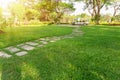 Smooth fresh green grass lawn with random pattern walkway of grey concrete stepping stone in garden of flowering plant Royalty Free Stock Photo