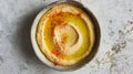 Smooth garleek hummus in a ceramic bowl, topped with olive oil and paprika, on a mottled grey surface for a rustic Royalty Free Stock Photo