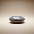 A smooth, gray, oval stone is centered against a soft beige background Royalty Free Stock Photo