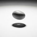 A smooth, gray stone is suspended in mid-air against a white gradient background Royalty Free Stock Photo