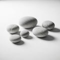 Smooth, gray stones of varying sizes are arranged on a plain white surface Royalty Free Stock Photo