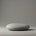 A smooth, grey stone with a rounded, flattened shape sits on a flat surface. The stone Royalty Free Stock Photo