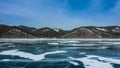 On the smooth ice of the frozen lake, patches of snow and cracks are visible.