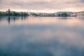 Smooth lake surface view towards the City of Geneva with a soft pastel dawn light.