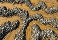 Smooth, multicolored pebbles form winding patterns on a sandy beach. The sand, Royalty Free Stock Photo