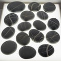 Smooth, oval-shaped black stones are arranged on a bright, backlit surface. Each Royalty Free Stock Photo