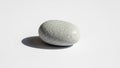 A smooth oval shaped grey pebble rests on a clean white surface Royalty Free Stock Photo