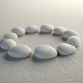 Smooth, oval-shaped white stones arranged in a circular formation on a textured san Royalty Free Stock Photo