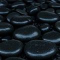 Smooth, polished black pebbles fill the image, varying in size and shape. The surface Royalty Free Stock Photo
