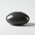 Smooth, polished black stone egg with a reflective surface. It rests on a plain white Royalty Free Stock Photo