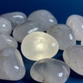 Smooth, polished white stones are arranged on a blue surface. They possess a Royalty Free Stock Photo