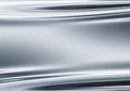 Smooth, reflective metallic surface with fluid-like ripples creating a Royalty Free Stock Photo