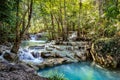 Rocks with cascading water make a series of beautiful short waterfalls in the dense forest of Erawan National park in Royalty Free Stock Photo