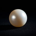 A smooth, round, white pearl with a glossy surface sits against a black background. Royalty Free Stock Photo