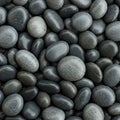 Smooth, rounded black pebbles are closely packed together, displaying a range of Royalty Free Stock Photo