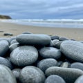 Smooth, rounded gray pebbles are stacked on a sandy beach, creating a focal point. T Royalty Free Stock Photo