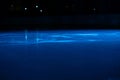 Smooth, shiny surface of an ice rink with reflected by spotlights. Dark empty ice arena with soft blue light. Concept of