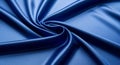 Smooth, silky fabric in a deep blue hue is arranged in an elegant swirl pattern. The material\'s Royalty Free Stock Photo