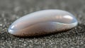 Smooth, translucent pebble-shaped object resting on coarse sand Royalty Free Stock Photo