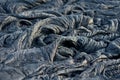 Smooth, undulating surface of frozen pahoehoe lava. Frozen lava wrinkled in tapestry-like folds and rolls resembling twisted rope