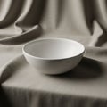 A smooth, white ceramic bowl sits on a draped fabric surface Royalty Free Stock Photo