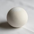 A smooth white ceramic sphere rests on a white surface casting a subtle Royalty Free Stock Photo