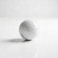 A smooth, white marble sphere rests on a plain surface, reflecting a soft light Royalty Free Stock Photo