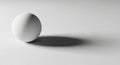 A smooth white sphere rests on a flat surface, casting a soft shadow to the right. The Royalty Free Stock Photo