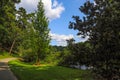 A smooth winding footpath through the forest near Candler Lake surrounded by lush green trees reflecting off the water