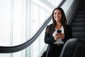 The smoothest business trip using the smartest apps. a businesswoman using a mobile phone while traveling down an Royalty Free Stock Photo