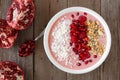 Smoothie bowl with pomegranates, raspberries, coconut, granola, on rustic wood