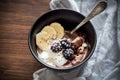 Smoothie bowl with vanilla and chocolate ice cream, blackberries, banana slices and chia seeds on the wooden background and checke