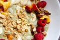 Smoothie fruit bowl with banana, peaches, raspberries, nuts, granola and pumpkin seeds for breakfast. Tasty oatmeal with fruits in Royalty Free Stock Photo