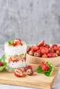 Smoothie with summer strawberry in glass jar and fresh berries in wooden bowl on a gray background